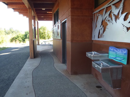 Two-tier drinking fountain at restroom - concrete walkway to picnic shelter - gravel path to trail